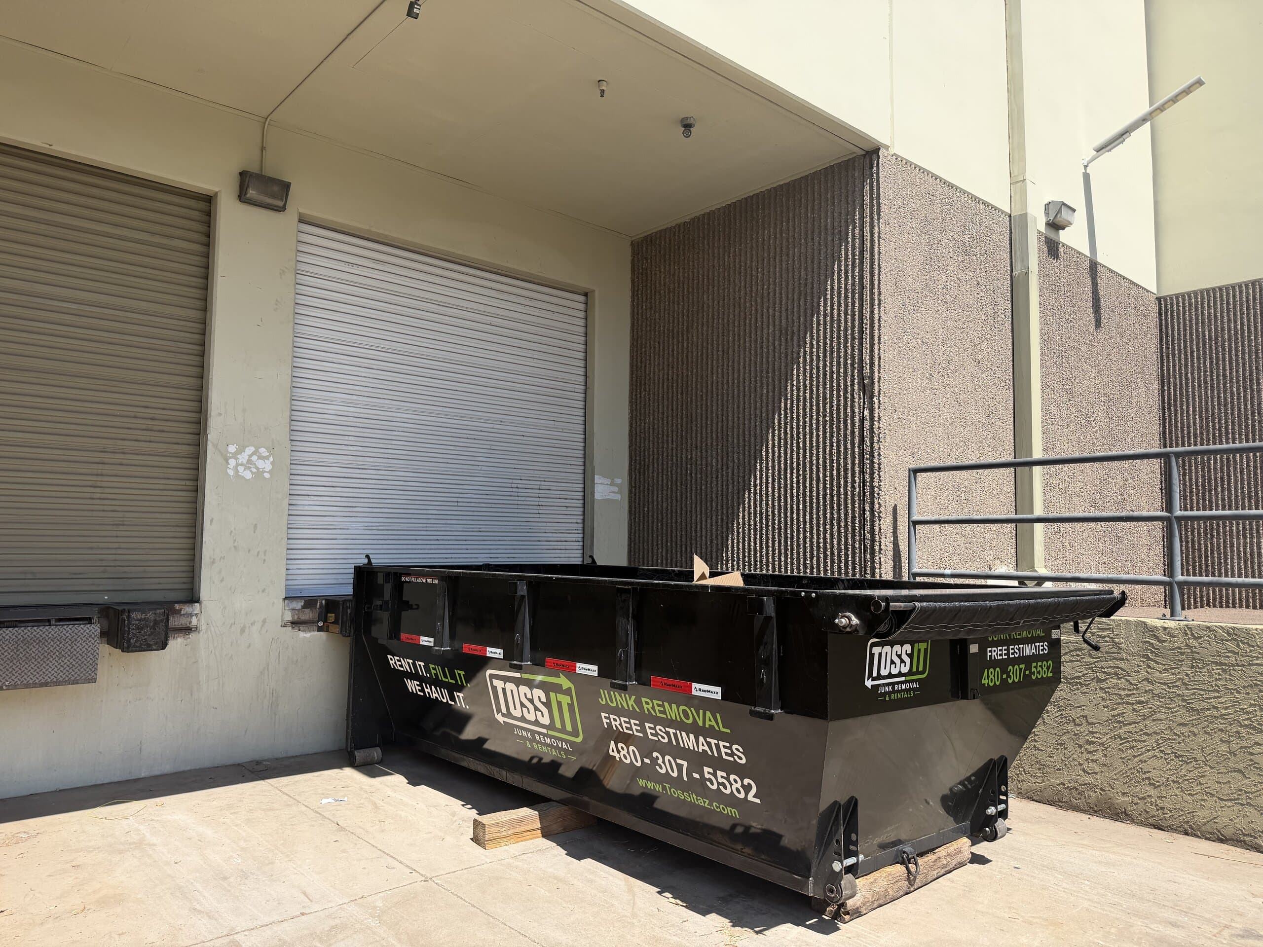 Toss It dumpster staged at a commercial loading dock
