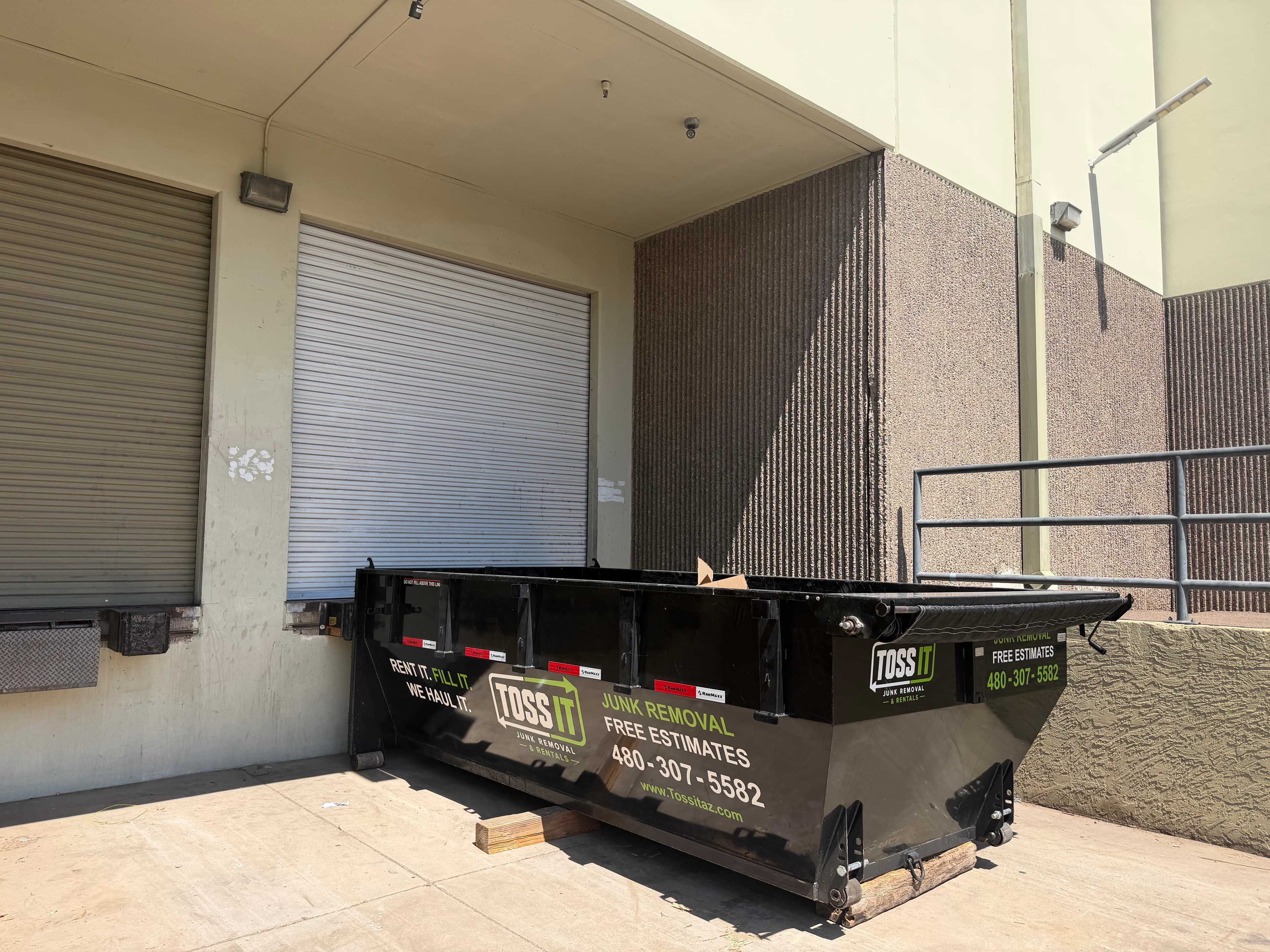Toss It dumpster staged at a commercial loading dock